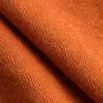 Close-up of the terracotta cotton single jersey knit of the custom made t-shirts, showing the stitch loops, yarn texture and a soft fold