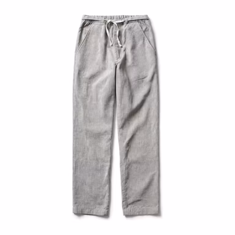 Chef trousers in a small light grey and white woven check, full front view with part-elastic drawstring waist, slanted side pockets and a loose straight leg