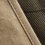 Close-up of the khaki cotton canvas weave, stitched seam and olive mesh panel of the fishing vest