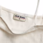 Close-up of the camisole back neck showing the cream woven YOUR BRAND label with its red rule line and size mark, stitched into the bound neckline