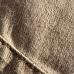 Close-up of the stone cotton twill weave and stitched seam of the bermuda shorts