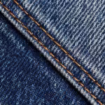 Close-up of the indigo denim diagonal twill weave with indigo warp over white weft and a felled seam with copper double stitching