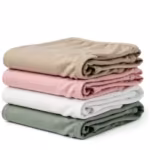 Folded stack of ladies cotton panties in stone beige, soft pink, white and sage green at a three-quarter angle, the folded layers and waistband edges showing