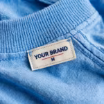 Close-up of the plain t-shirt inside back neck with woven YOUR BRAND label and collar stitching