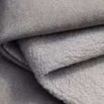 Close-up of the grey softshell cloth folded at the edge, showing the fine matte woven face bonded to the brushed fleece backing