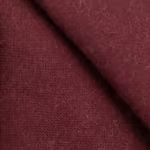 Close-up of the burgundy poly-cotton plain weave of the work tabard, showing the warp and weft yarn structure, natural fibres and a bound seam